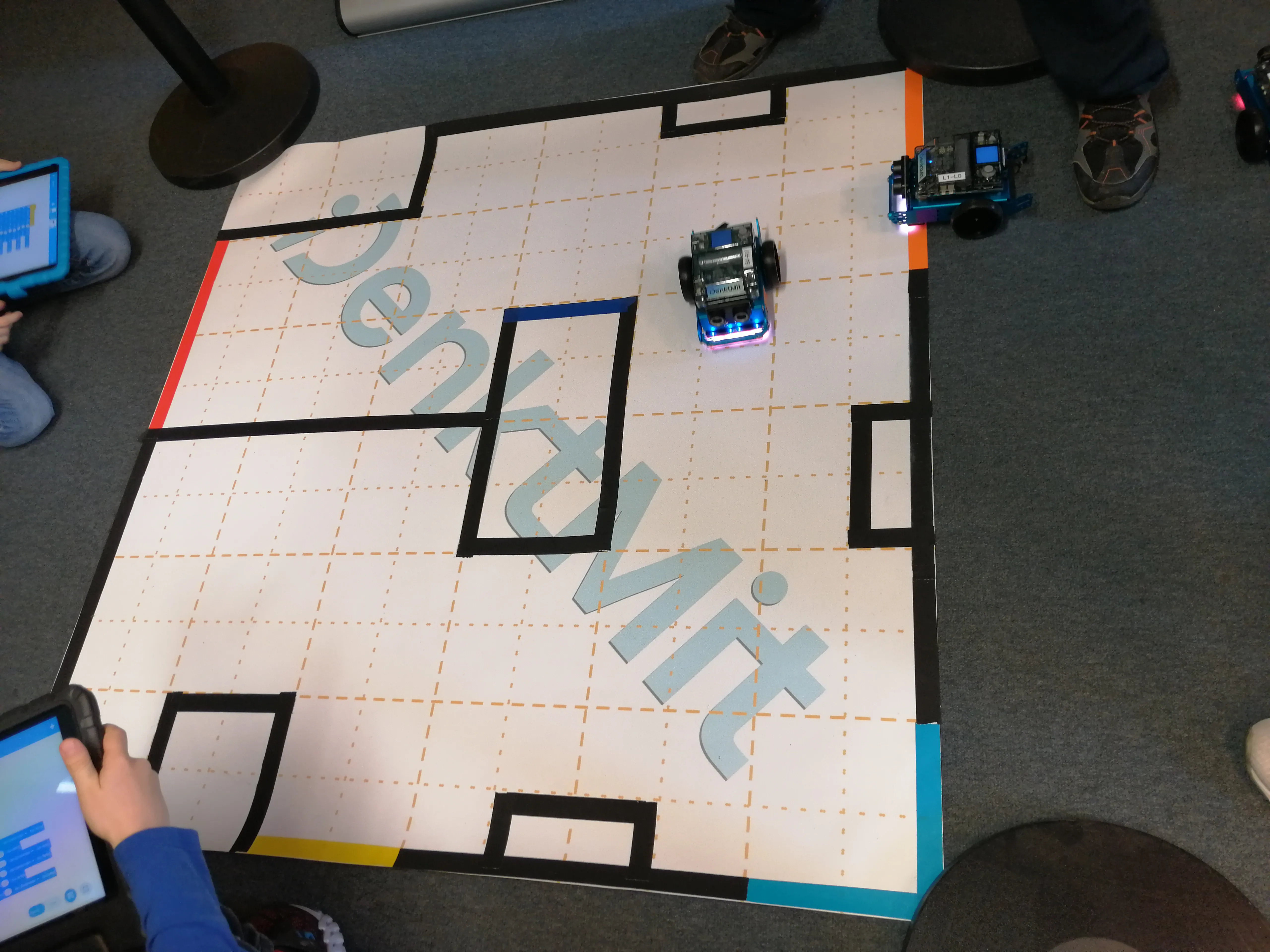 Zwei mBot2 Lernroboter auf einem Parcours mit DenktMit-Logo
